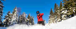 Tjej på snowboard som sprutar upp snö med brädan