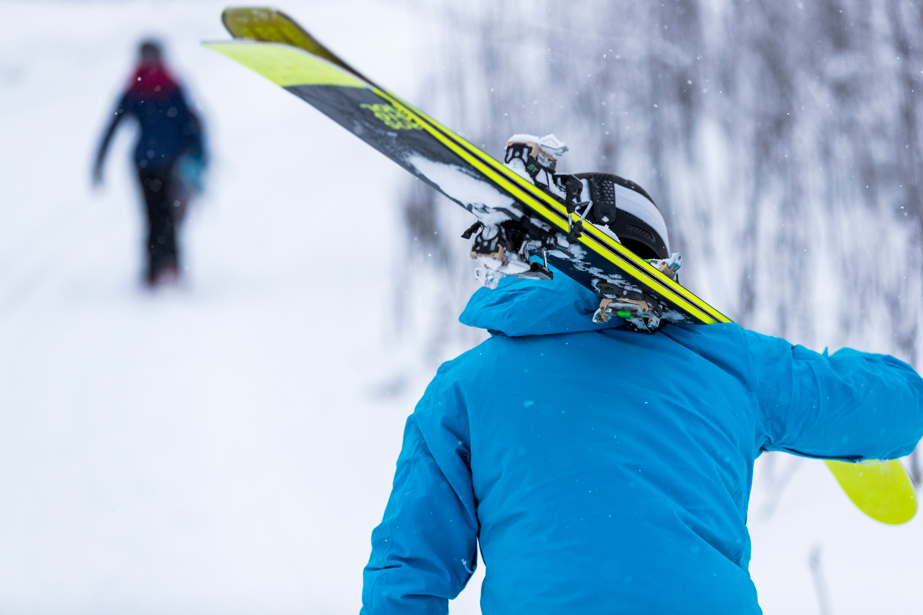 Slalomåkare som går med slalomskidor på axeln
