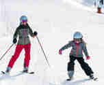 Mor och dotter på slalomskidor åkandes nedför pist
