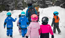 Aktivitetslärare som går med massor av barn i snön