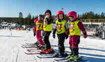 Barn på led i slalomutrustning och skidskolevästar