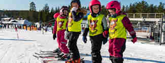 Barn på led i slalomutrustning och skidskolevästar